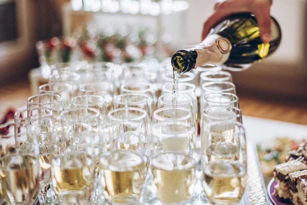 champagne golden glasses. waiter pouring champagne in stylish glasses at luxury wedding reception. rich celebration. expensive catering and service at feast. new year and christmas