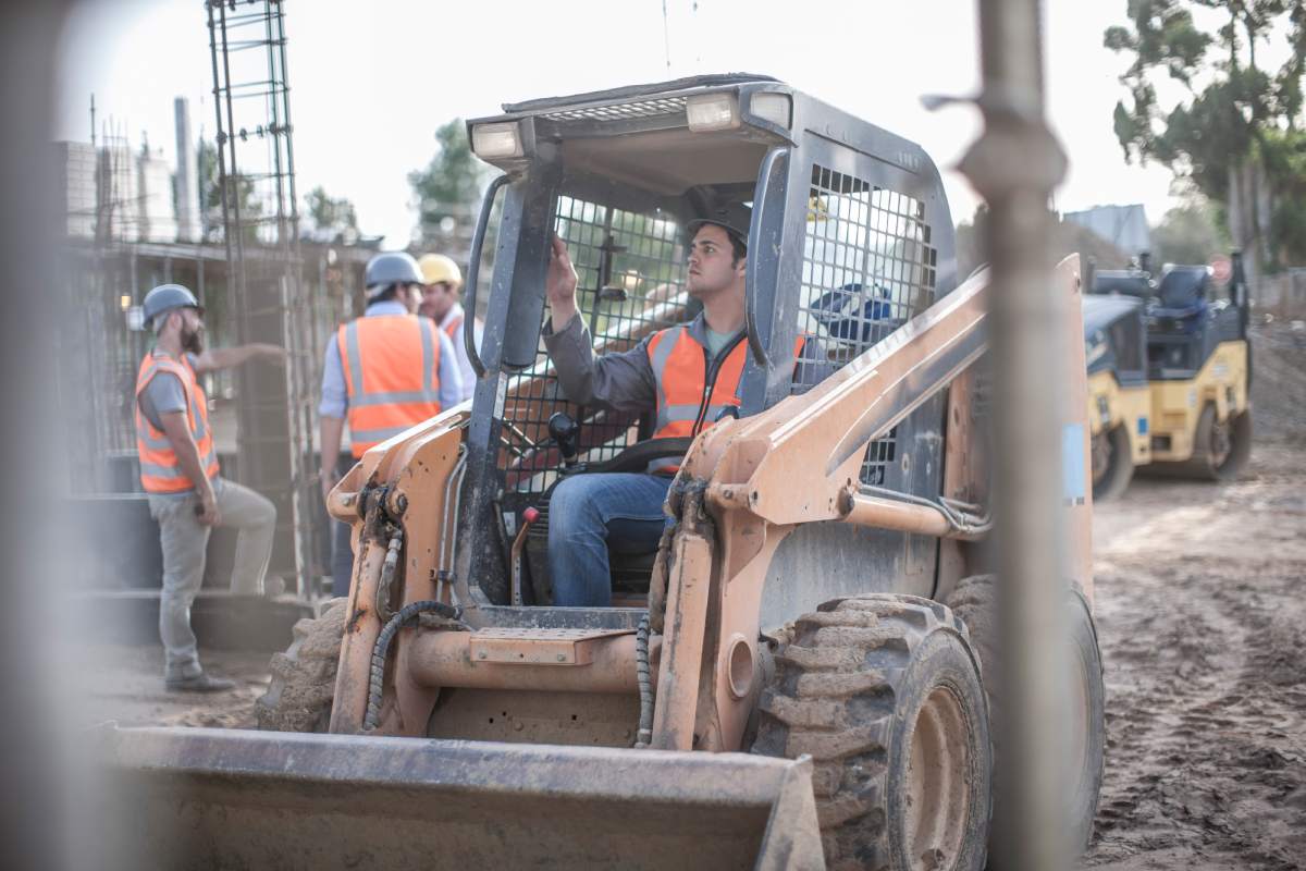 Construction worker driving excavator on construction site