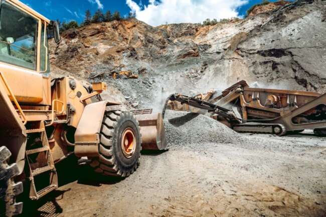 Wheel loader excavator bulldozer with backhoe loading gravel on construction site